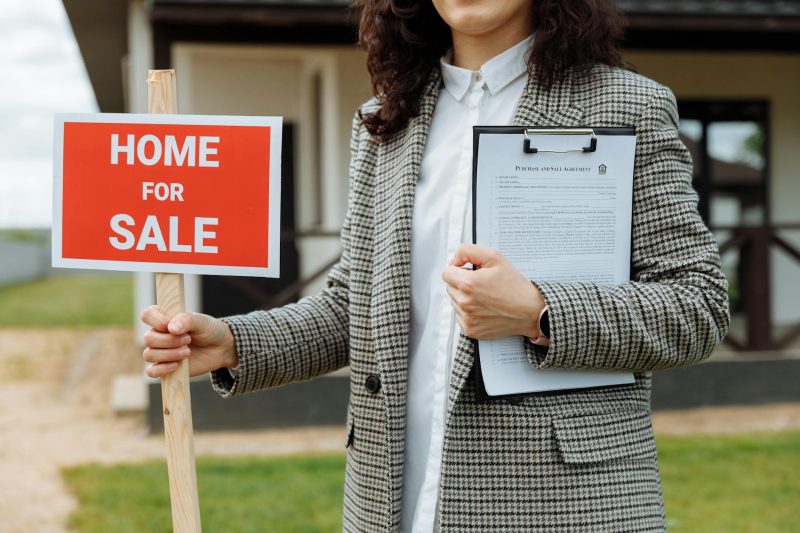 A real estate agent holding a home for sale sign